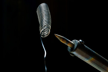 Naklejka premium heated soldering iron and solder. dark background. close-up