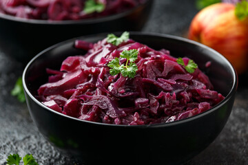 Obraz na płótnie Canvas Braised Red Cabbage with apples and redcurrant in black bowl