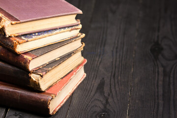 Vintage leather books stack on old rustic wooden surface