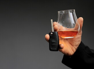 drink driving with hand holding key and alcohol drink on grey background stock photo