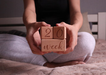 Pregnant woman holding cubes with 20 weeks gestation