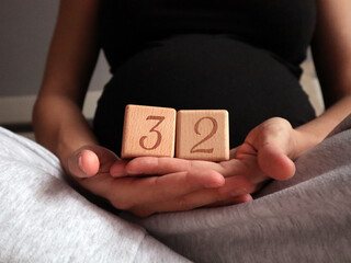 Pregnant woman holding cubes with 32 weeks gestation
