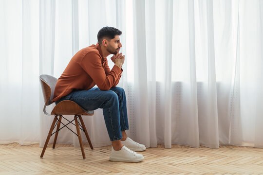 Pensive Arab man sitting on chair and thinking