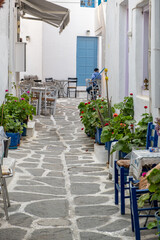Fototapeta na wymiar Paros island Naousa Greece. Building cobblestone alley outdoor cafe tavern summer day. Vertical