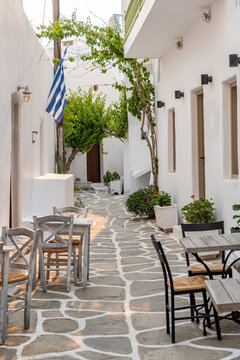 Paros island Naousa Greece. Building cobblestone alley outdoor cafe tavern summer day. Vertical