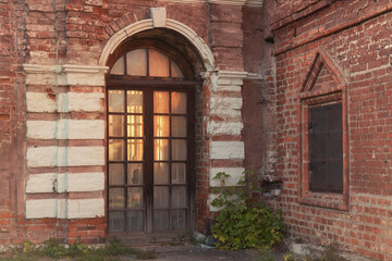 A brick building glass door inside an arch in the Krutitsy Metochion by autumn day