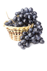 A bunch of blue grapes in a basket isolated on a white background