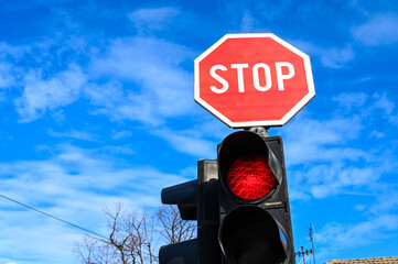 Stop sign and red light at a traffic light at an intersection. Red stop sign on the road. Traffic...