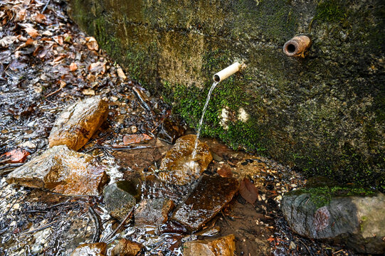 Natural water pouring from metal pipe. Pipe pouring fresh drinkable water in mountain. 