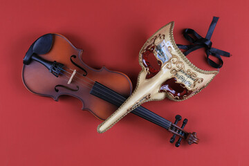 theatrical mask and violin isolated on red background