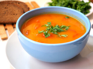 Vedic cooking. Vegetarian pumpkin soup with fresh herbs in a blue bowl. Close-up