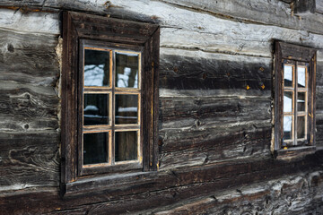 Fototapeta na wymiar Rustic wooden house made of round logs. Abandoned villages and houses. Ancient window design. Wooden window frame. Snow covered village. Age-old buildings. Professional photography.