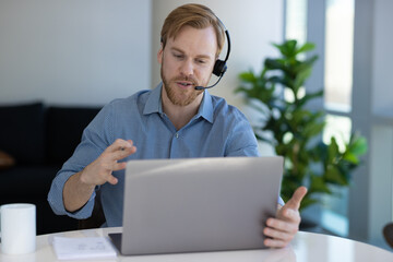 Caucasian man at home remote working on laptop computer talking with his colleague