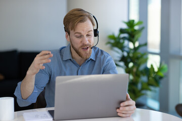 Caucasian man at home remote working on laptop computer talking with his colleague