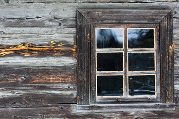 Obraz na płótnie Canvas Rustic wooden house made of round logs. Abandoned villages and houses. Ancient window design. Wooden window frame. Snow covered village. Age-old buildings. Professional photography.