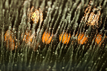 Selective focus to the water drop inside the car, with some lights on in the background