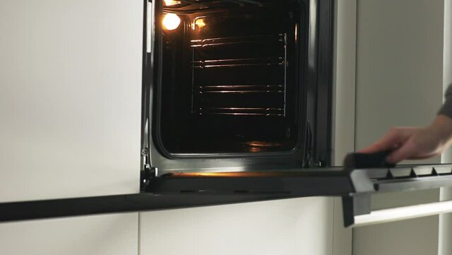 Woman cleaning electric oven after cooking