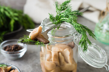 Pickled mushroom on a fork on a jar with boletus and dill and in a glass jar on the table. Vegetarian organic food. Close-up