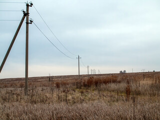 poles with electrical wires stand in the field