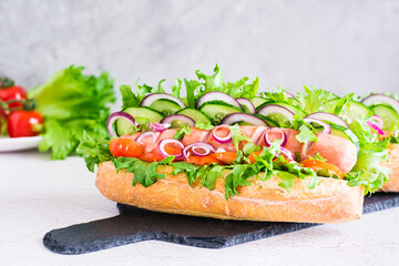 Ready to eat hot dogs with sausage and vegetables on a slate on the table. Fast food for a snack. Close-up