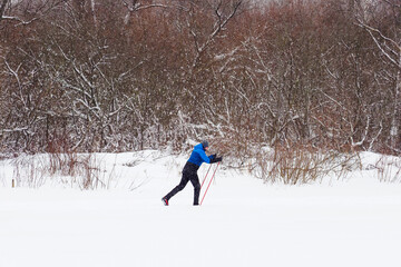 Man runs on skis in the lake icy, winter woods on the background. Ice course skiing. healthy lifestyle concept