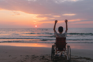 Behind of young man with disability looking sunset on the sea beach at summer, Positive photos give...
