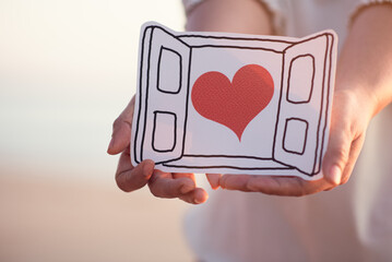 Woman's hands holding paper cut of heart in window,encouragement,world mental health...