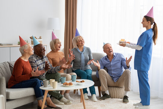 Excited elderly people having birthday party at nursing home, panorama