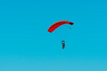 Tandem parachute jump. Silhouette of skydiver flying in blue clear sky. Concepts of extreme sport...