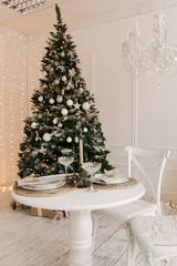 Stylish bright interior of the living room with a Christmas tree and a festive table