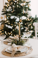 Stylish bright interior of the living room with a Christmas tree and a festive table