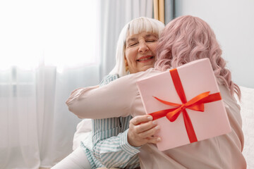 International Women Day. Beautiful happy caucasian daughter giving mother gift box for mothers day...