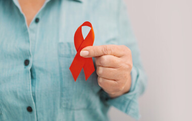 Woman hands holding red ribbon, hiv awareness concept, world AIDS day, world cancer day