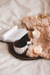 Cosy winter or autumn atmosphere: cup of black tea with paper book and knit cloth fabric on wooden...