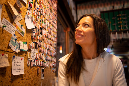 Young woman sitting in a bar looking at a wall with annotations and passport photos