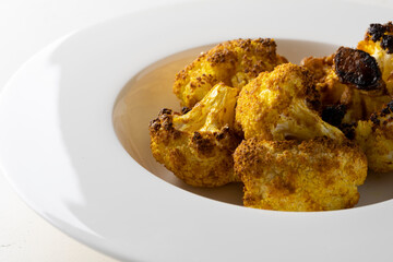 baked cauliflower with curry on white plate