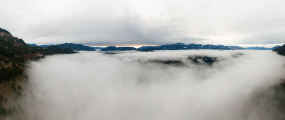 Aerial Panoramic View of Canadian Mountain Landscape covered in fog over Harrison Lake. Winter Season. British Columbia, Canada. Nature Background Panorama