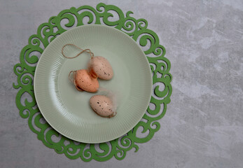 Three Easter eggs on a greenish plate and decorative tablet