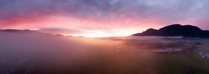 Fototapeta na wymiar Aerial Panoramic View of Farm lands and Canadian Mountain Nature Landscape. Dramatic Winter Sunset. Located near Chilliwack and Abbotsford, British Columbia, Canada.