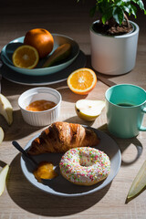 Healthy breakfast. Croissant, donut, coffee, jam, fruits: oranges and pears.