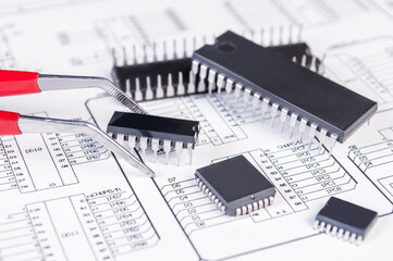 Electronics components and tweezers on background of  schematic circuit diagram. Concept for development and design of electronic devices.