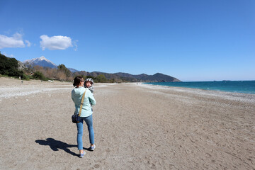 tourist family - mother and little son walks on the Cirali beach in Turkey
