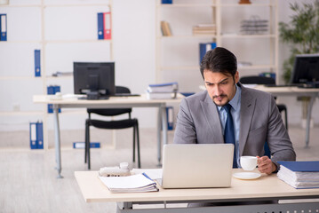 Fototapeta premium Young male employee drinking coffee during break