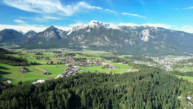 Circling drone shot of an alpine landscape in Austria, with villages and snow covered mountain peaks. Traveling through the Alpbach Valley, Tyrol.