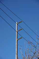 Electricity distribution pylon and power lines under blue sky