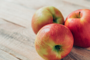 Three large red-yellow apples close-up on wooden table. Copy space.