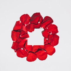 Circle made of red rose petals with copy space on light background. Flat lay. Top view.