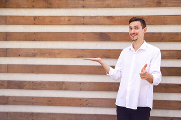 lifestyle, emotions, advertisement, gesture and people concept - happy European bearded man holding something in the palm and pointing finger at the camera on a brown ribbed background with copy space