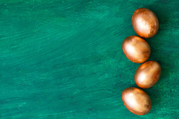 Golden Easter eggs and golden branches, reeds on a green watercolor background. Banner. Layflat. Space for text 