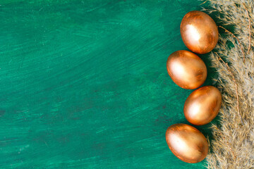 Golden Easter eggs and golden branches, reeds on a green watercolor background. Banner. Layflat. Space for text 